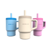 Drei wiederverwendbare Becher mit Henkeln und Strohhalmen in den Farben Blau, Beige und Rosa, die jeweils mit der Aufschrift „Kochblume“ versehen sind, sind nebeneinander auf einem schlichten weißen Hintergrund angeordnet.