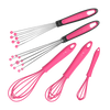 Auf einem weißen Hintergrund sind fünf Schneebesen mit rosa Griffen angeordnet. Zwei davon haben Metalldrähte mit kugelförmigen Enden, und drei sind komplett rosa, in verschiedenen Größen und durchgehend mit Silikon beschichtet.