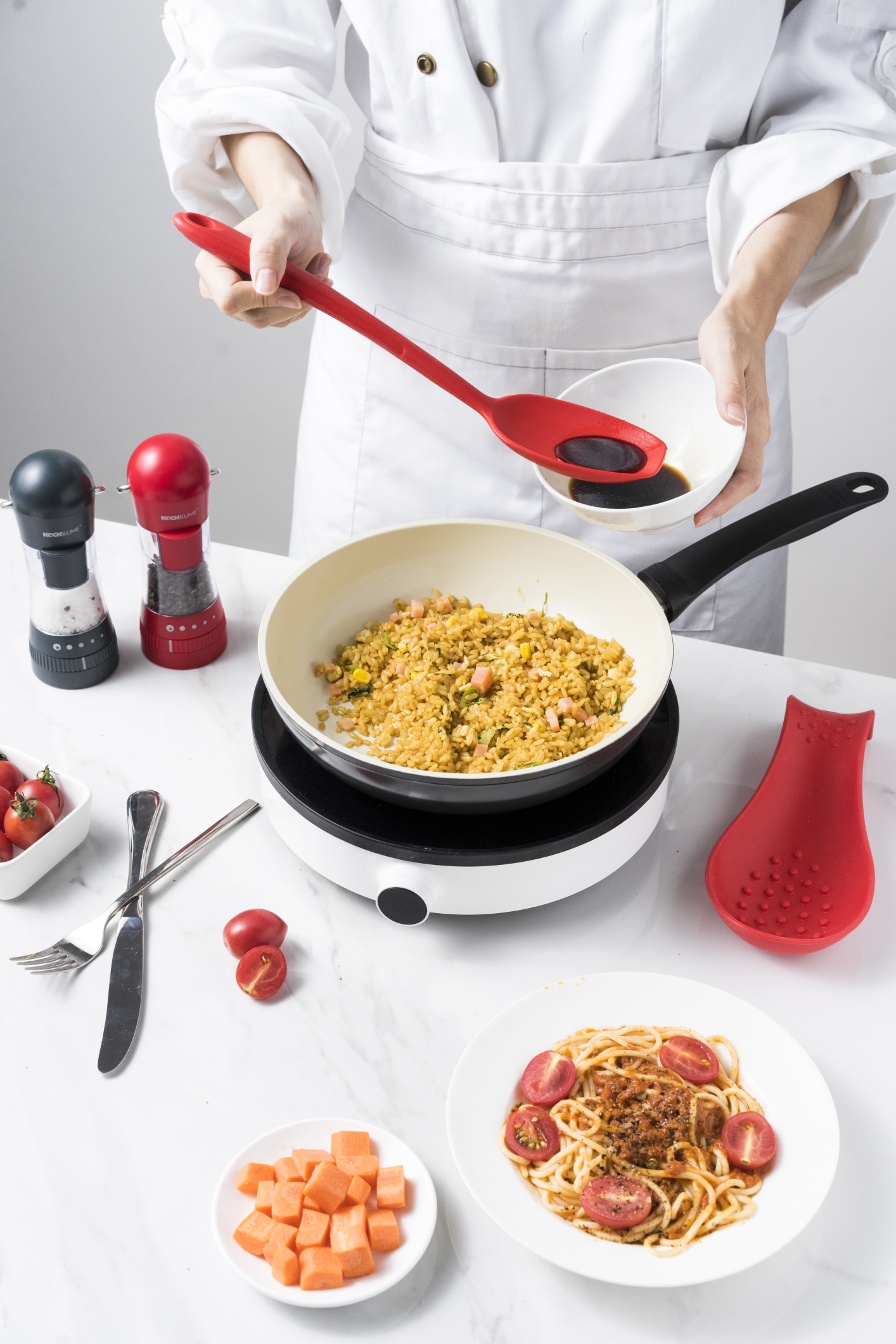 Eine Hand taucht einen roten Silikonlöffel in einen Topf mit Tomatensuppe neben einem Teller mit Croutons und frischen Tomaten auf einer Küchenarbeitsplatte